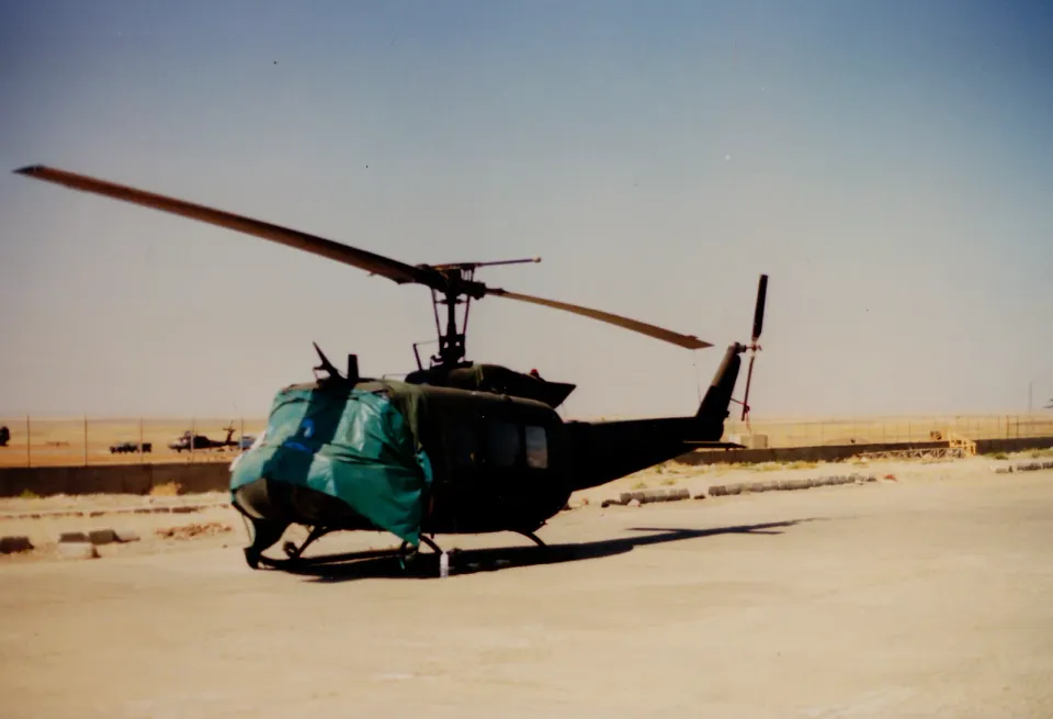 A UH-1H Huey covered against an approaching sandstorm